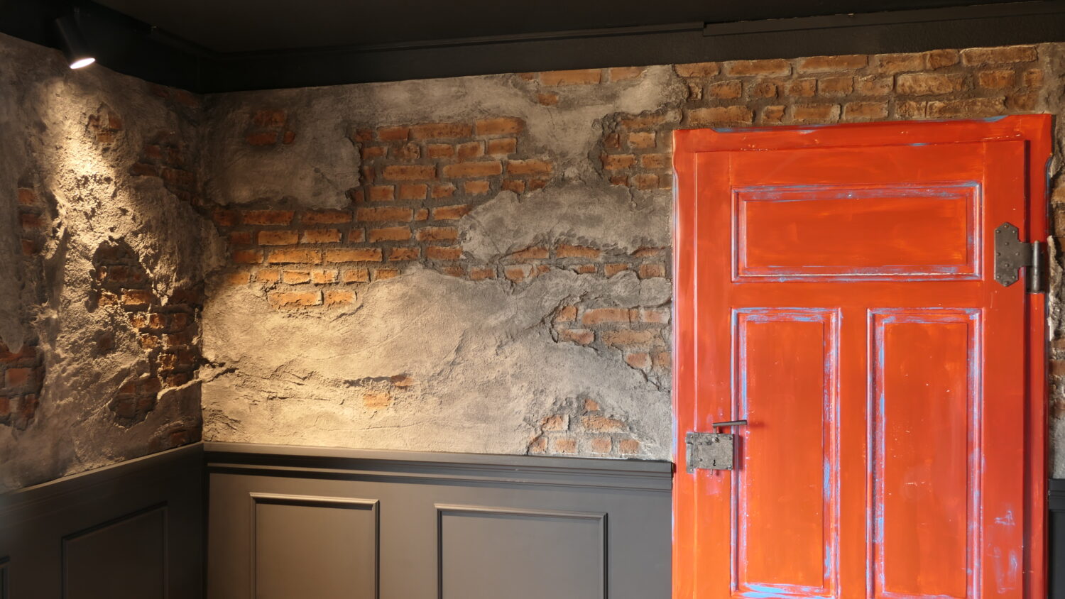 Wandgestaltung mit sichtbarer Ziegelstruktur, Betonputz und dunklen Zierpaneelen – stilvoll umgesetzt mit Wandpaneelen von Holz Hertel