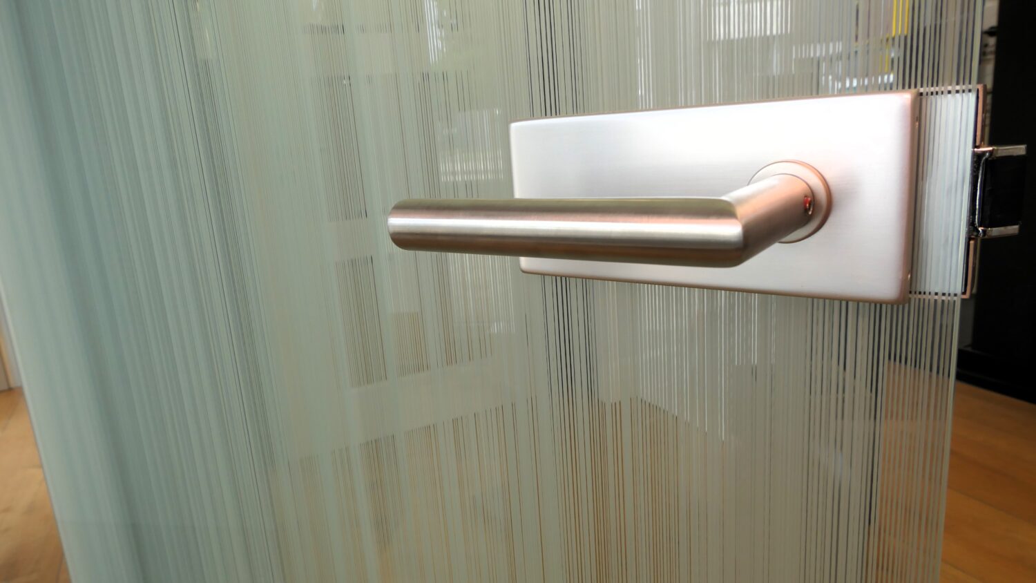 Glastür mit vertikaler Struktur und Edelstahlgriff in Nahaufnahme