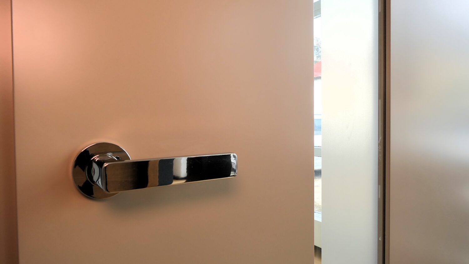 Teilgeöffnete Glastür mit satinierter Oberfläche und verchromtem Türgriff